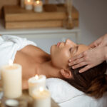 Young beautiful brunette girl having face massage relaxing in spa salon. Eyes closed. Copy space.